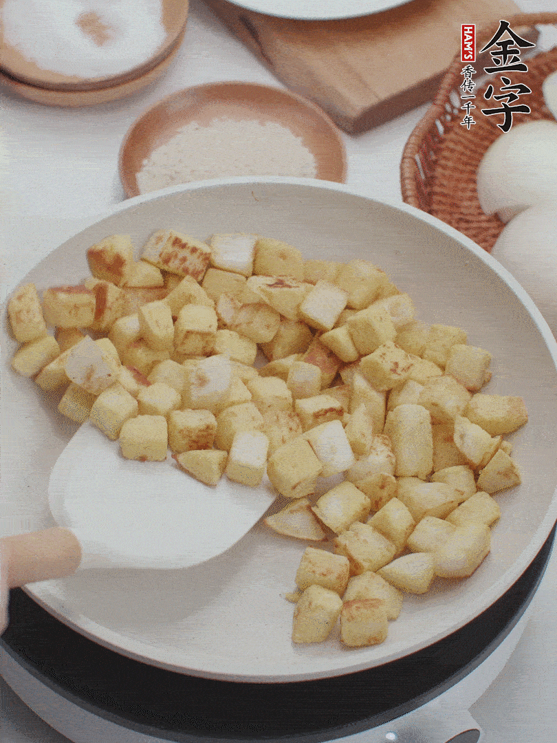 起鍋熱油，倒入饅頭丁，小火煎至蛋液凝固定型再翻面，饅頭丁部煎至金黃時盛起待用。