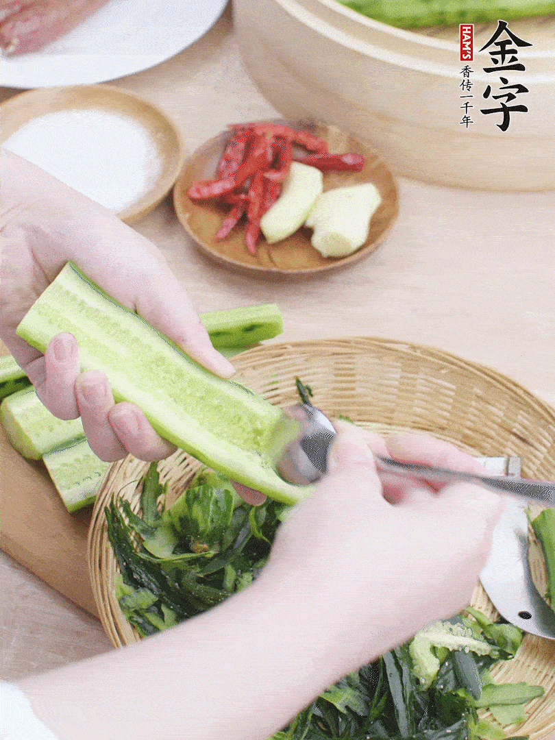 黃瓜削皮，對(duì)半切開，勺子挖去內(nèi)瓤，斜刀切片。青蒜斜刀切段。
