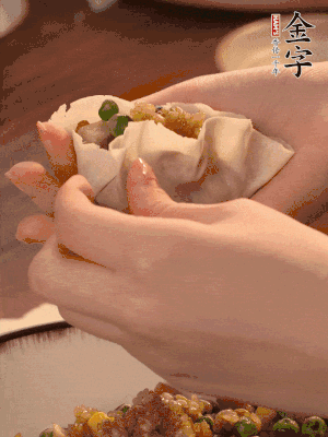 取一大勺餡料放進(jìn)餃子皮里，用大拇指按住頂部餡料，再用虎口掐出形狀。